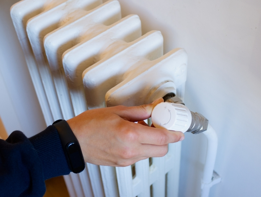 En hand som justerar värmen på ett element.