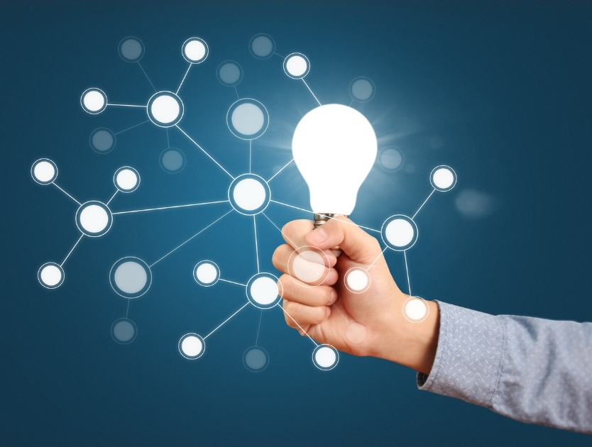 En hand som håller upp en upplyst glödlampa.